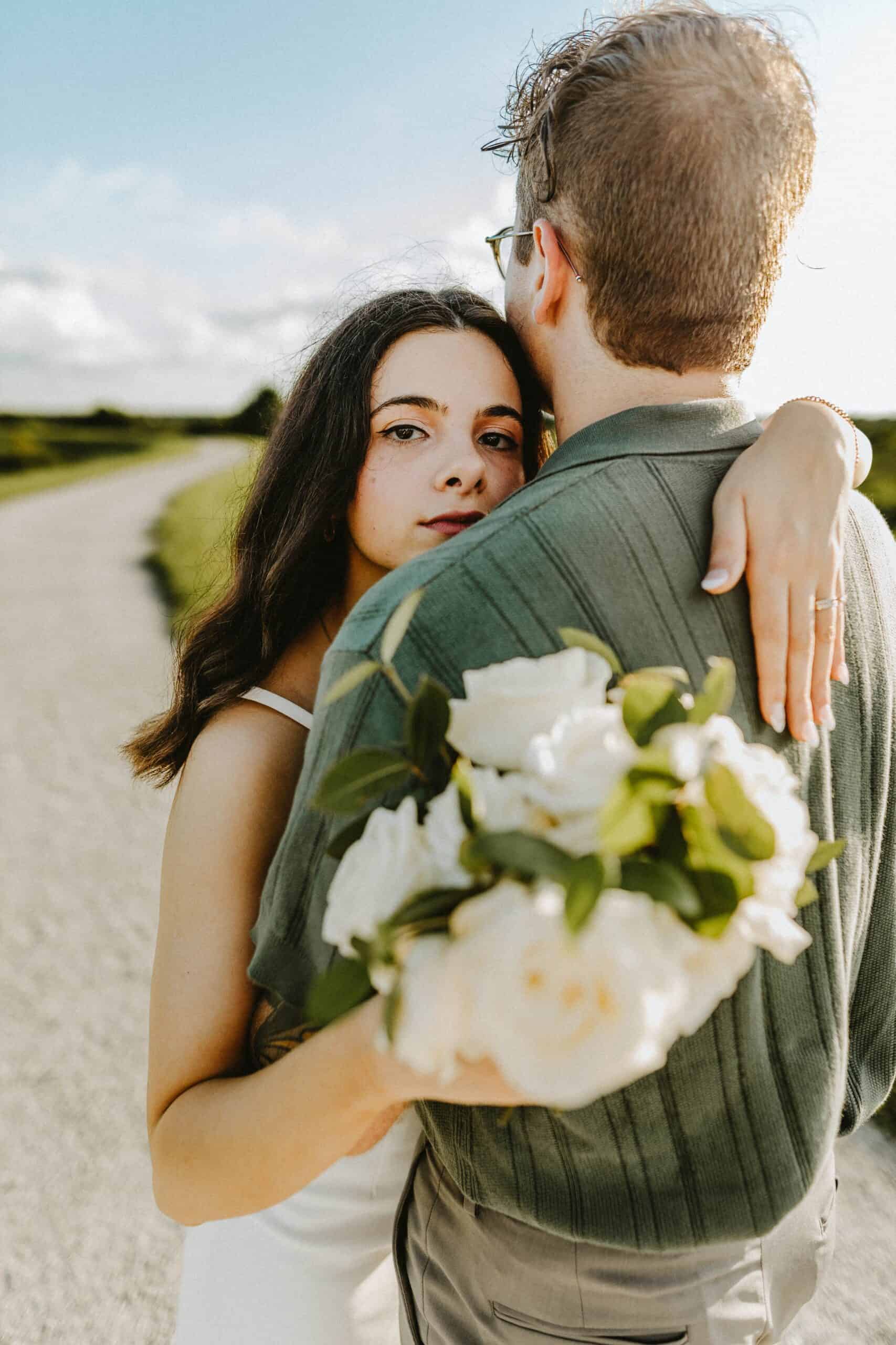girl hugging a guy with a bouquet of flowers