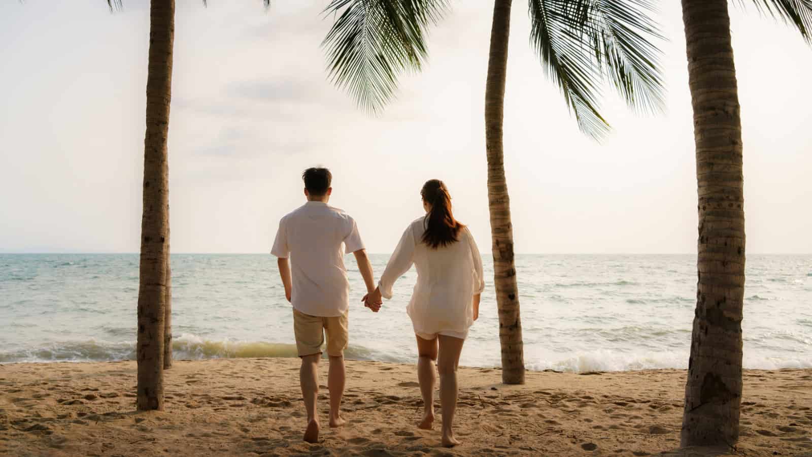 Asian couple is running and holding hands on a beach