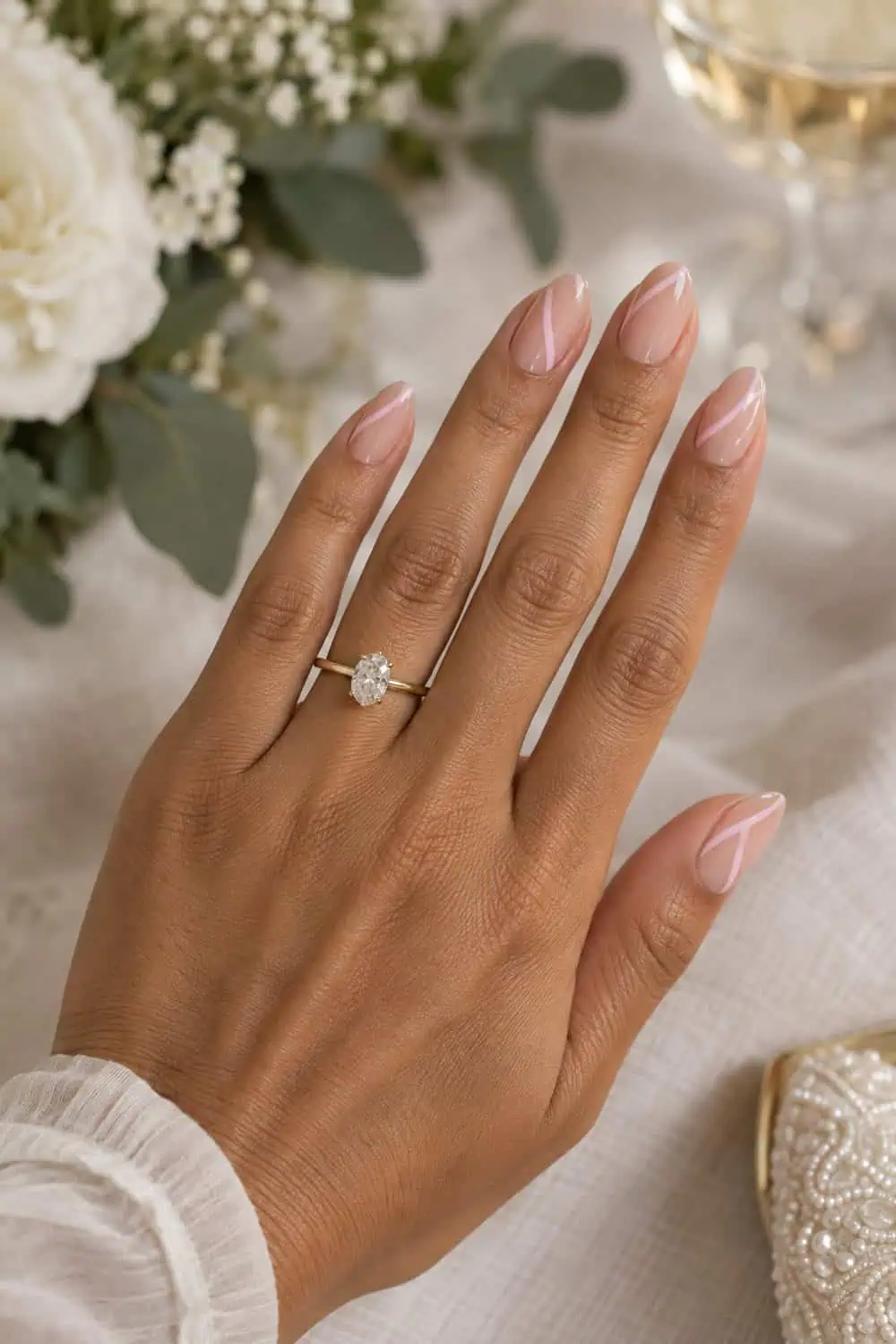 Wedding guest olive-toned hand with medium almond nails, clear gloss and thin pale pink diagonal lines with open negative space, ivory background