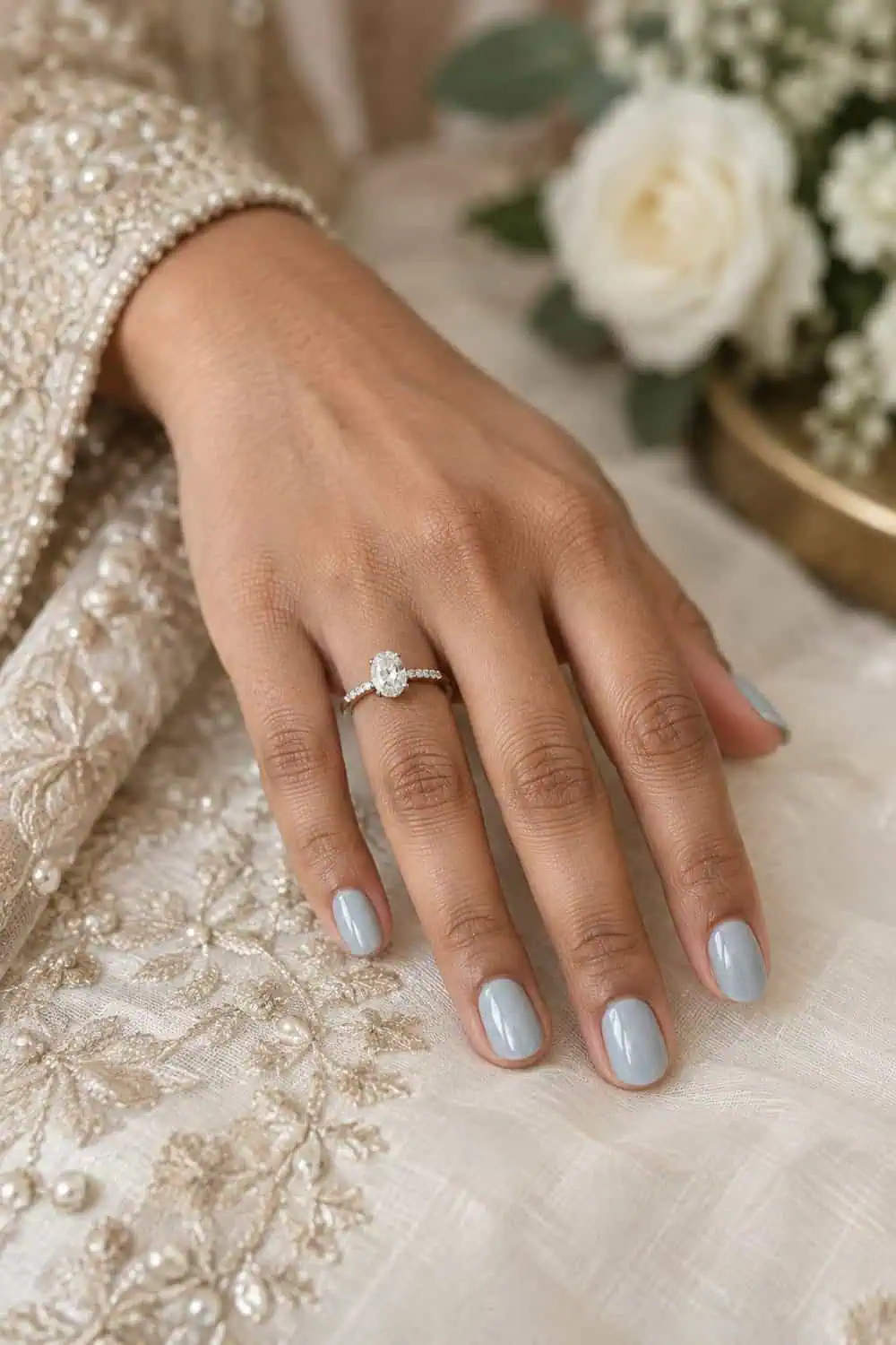 adult bride's South Asian hand with short oval nails painted translucent icy blue with subtle glaze, silver ring visible