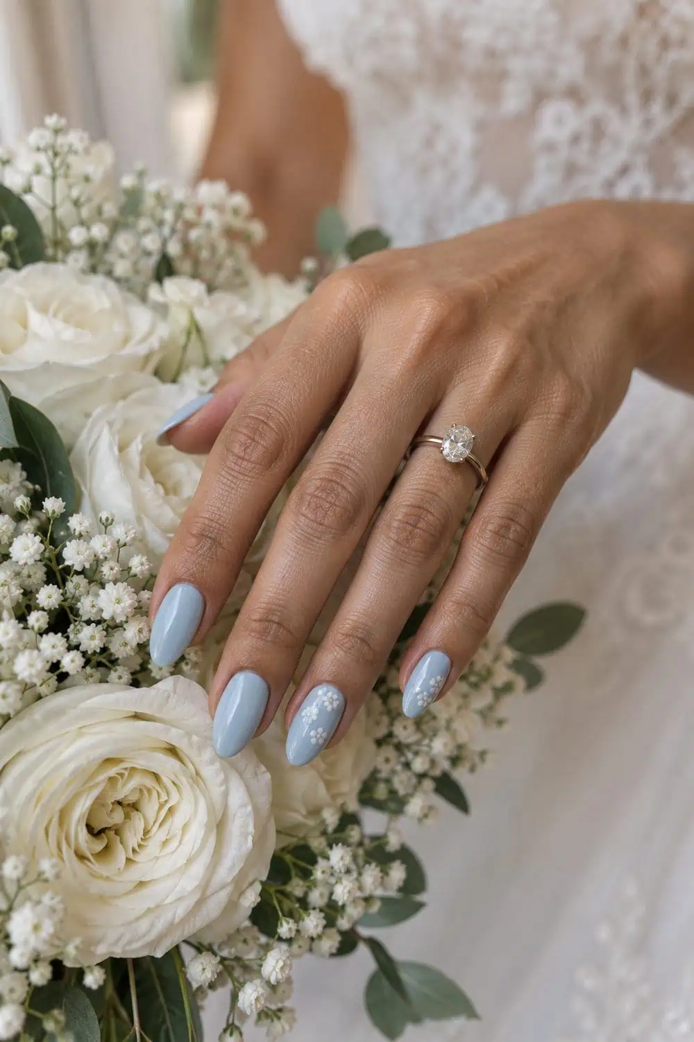adult bride's olive-toned hand with medium almond nails painted powder blue, tiny white blossom clusters on two nail corners, white bouquet