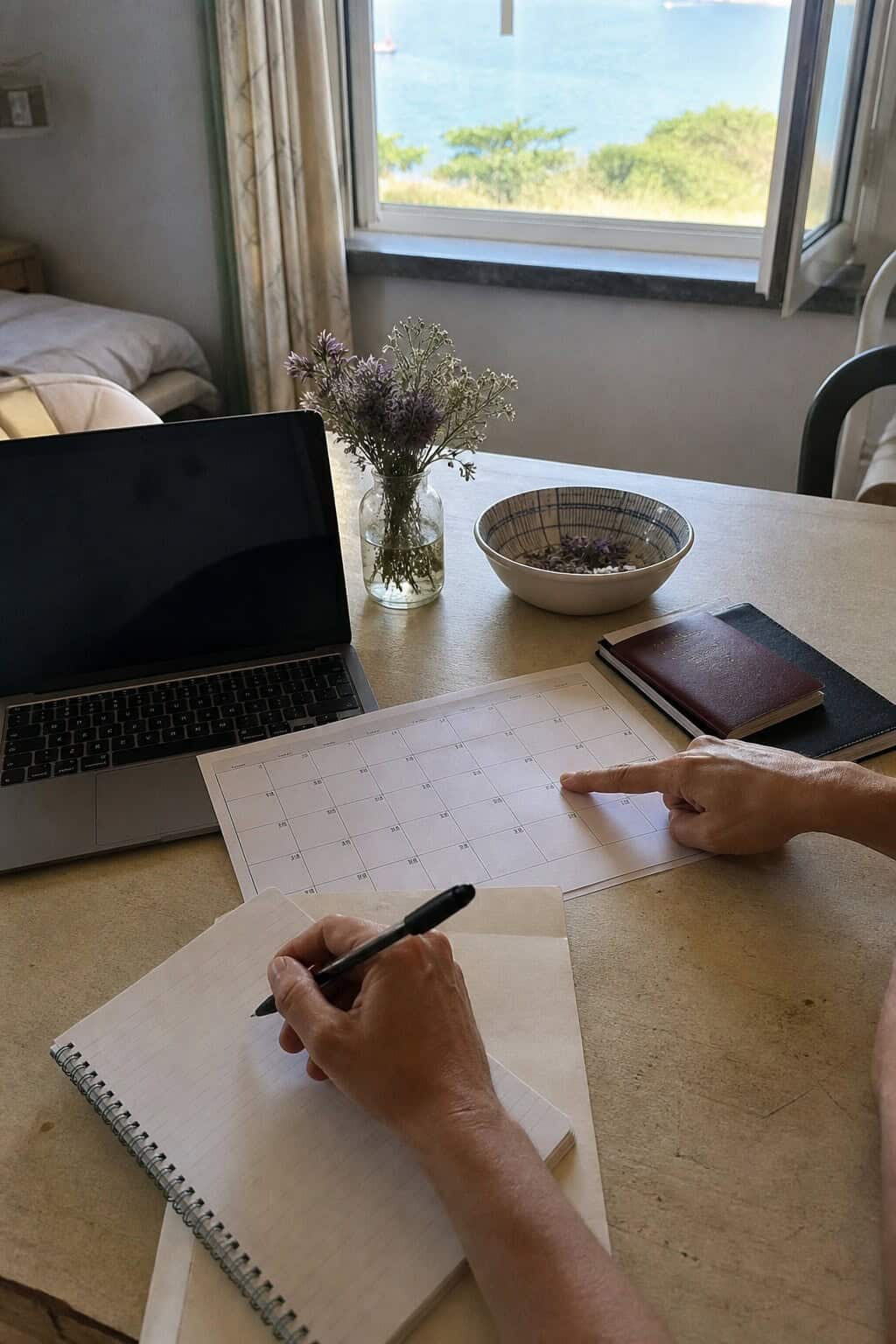 Couple planning an affordable destination wedding with a calendar, notebook, laptop, and passports