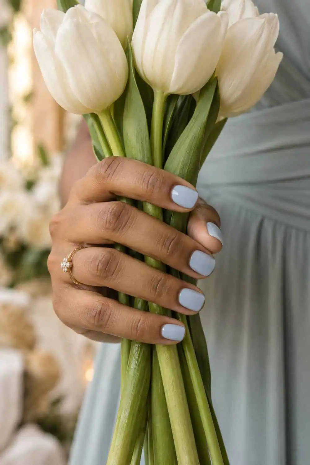 Bridesmaid South Asian hand with short squoval nails painted creamy pale dusty blue, holding white tulips