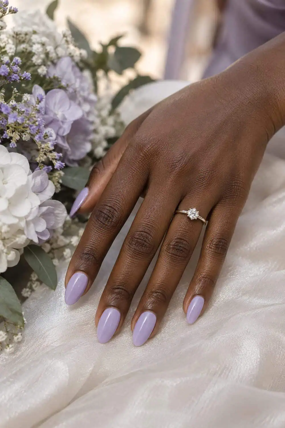 Bridesmaid dark-brown hand with medium almond nails painted solid soft lilac, white and lavender flowers nearby