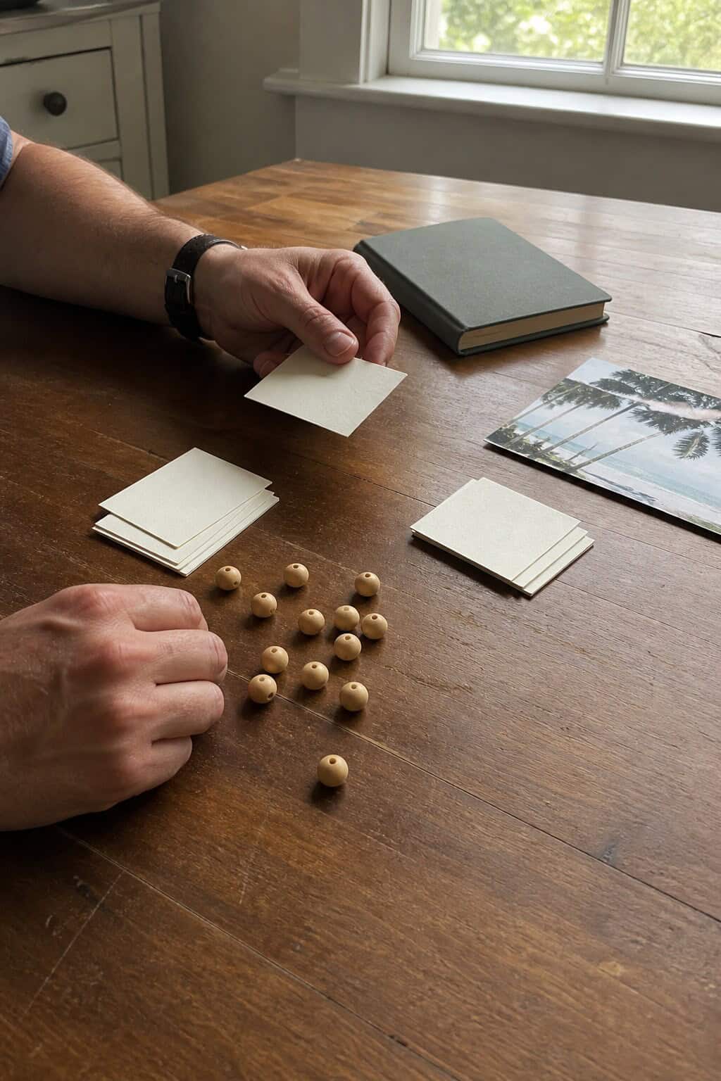 Hands sorting place cards and wooden markers while planning a small destination wedding guest list